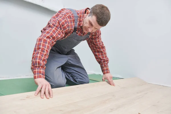 Lavoratore posa pavimento in laminato rivestimento a casa ristrutturazione — Foto Stock