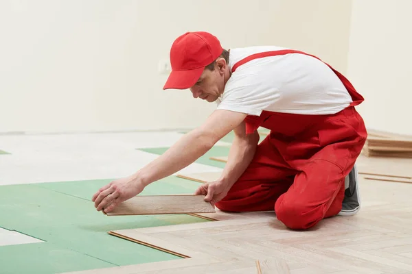 Работник кладет ламинат напольное покрытие при ремонте дома — стоковое фото