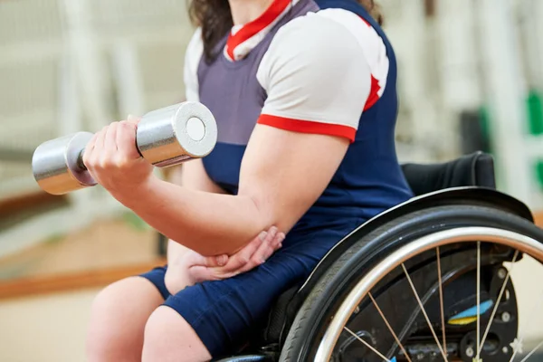 Gehandicapte vrouw in rolstoel tillen gewicht in de sportschool. Activiteiten voor gehandicapten — Stockfoto