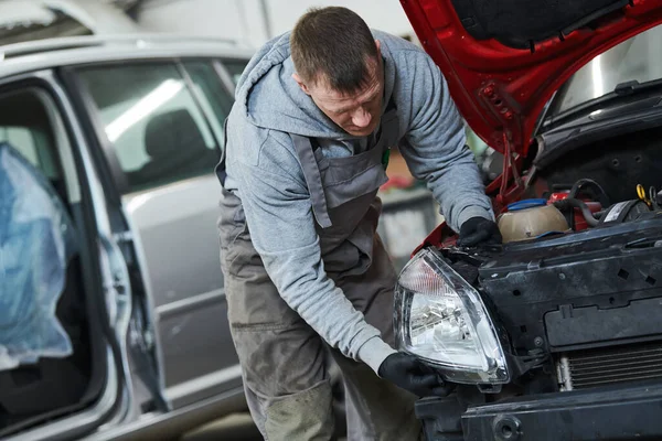 Auto-Service. Techniker beim Zusammenbau einer Autoscheinwerfer-Lampe. Karosseriereparatur für die Versicherung — Stockfoto