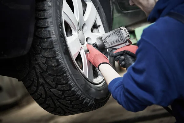 Serviço de automóvel. Trabalhador aparafusar uma roda de automóvel. Manutenção da ruptura ou substituição do pneu — Fotografia de Stock