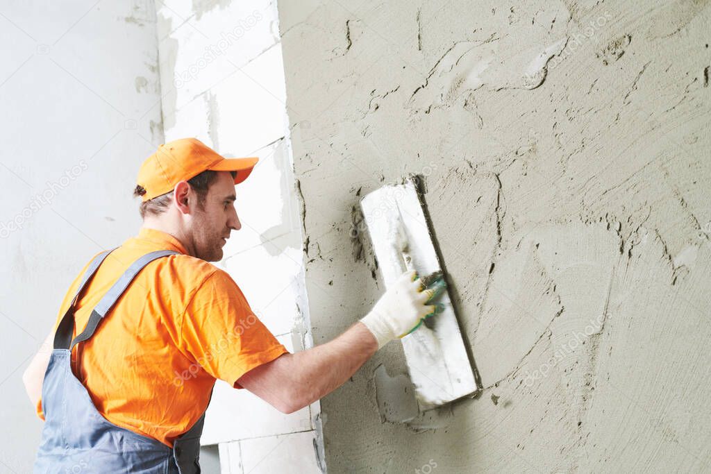 Renovation at home. Plasterer smoothing plaster on wall.