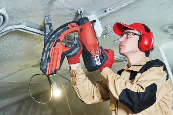 Electrician service. Installer nailing tube holder for cable conduit — Stock Photo, Image