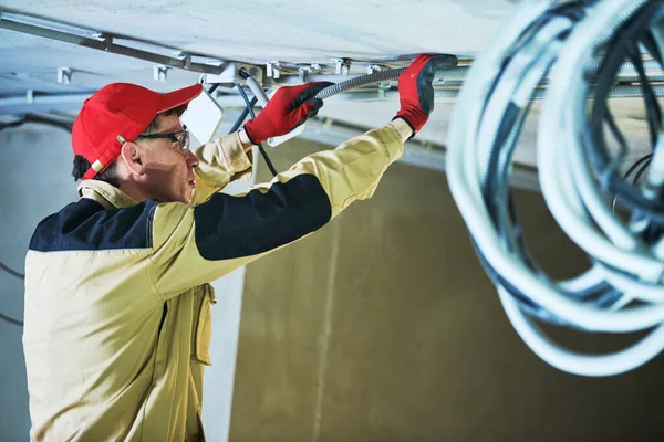 Elektricien dienst. Installateur werkt met kabel op plafond — Stockfoto