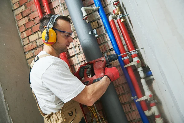 Loodgieter boren een gat in de muur voordat water apparatuur installatie — Stockfoto