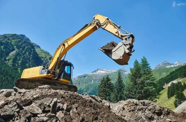 Excavadora cargadora máquina en la construcción movimiento de tierras trabajo en las montañas —  Fotos de Stock