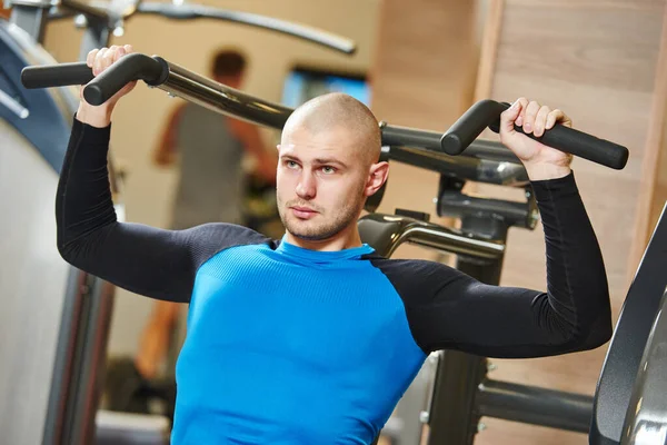 Masculino fazendo excercise no treinamento máquina no ginásio — Fotografia de Stock