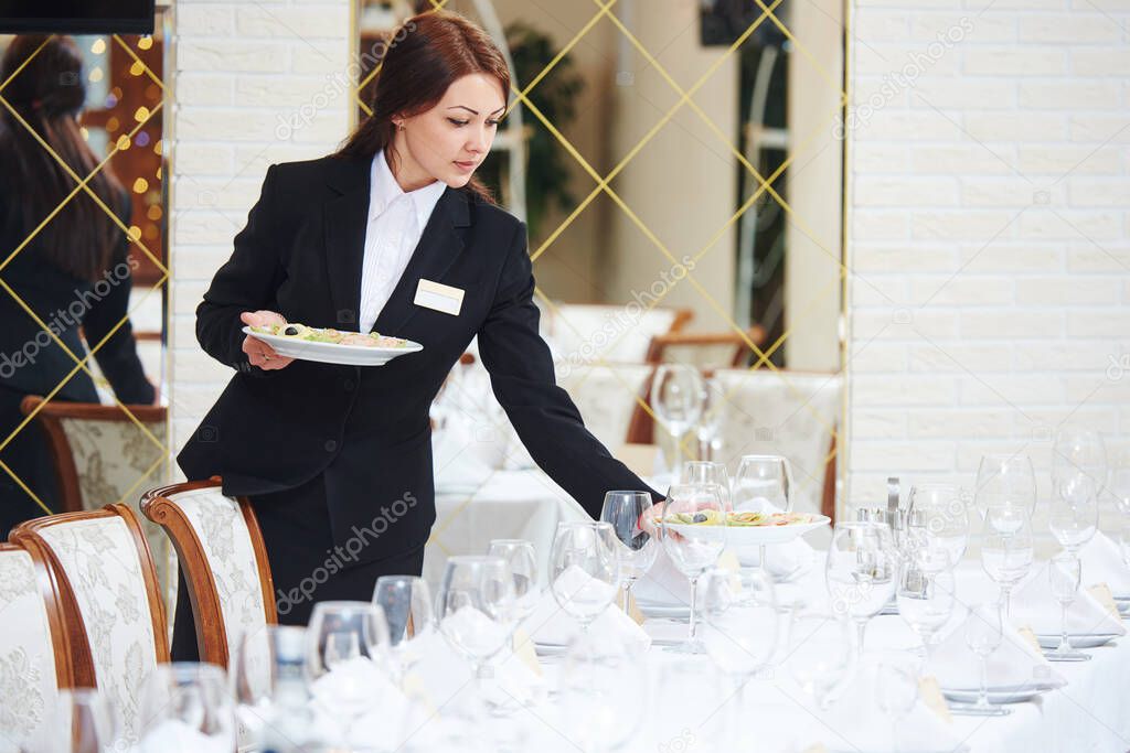 Restaurant waitress serving table with food