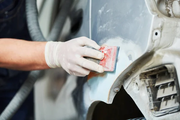 Auto repairman plastering and sanding autobody bonnet — Stock Photo, Image