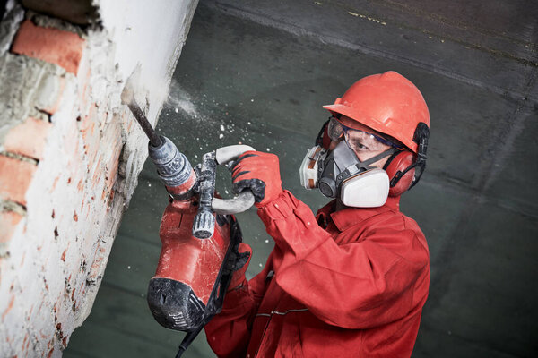 worker with demolition hammer breaking interior wall