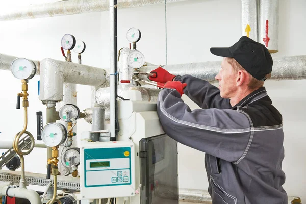 Engenheiro de aquecimento ou encanador na sala de caldeiras instalando ou ajustando manômetro — Fotografia de Stock