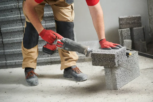 Maurer schneidet Keramikbetonblöcke mit Säge an Mauern — Stockfoto