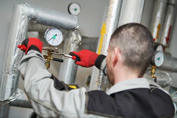 Heating engineer or plumber in boiler room installing or adjusting manometer Stock Photo