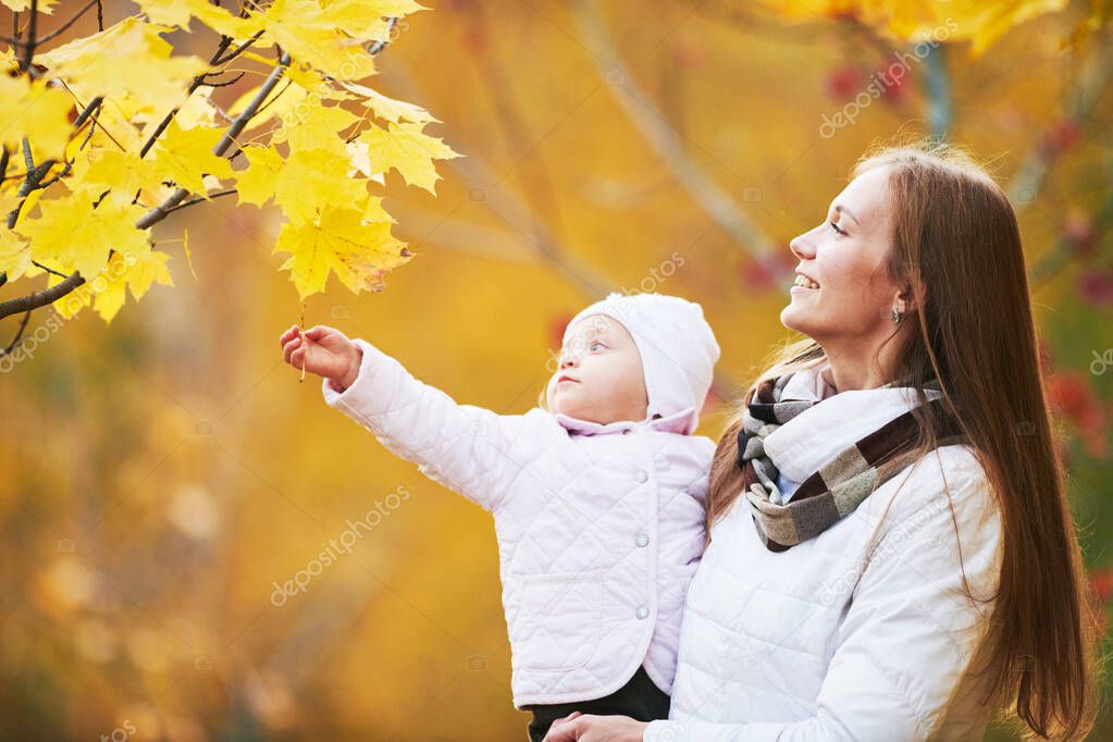 mother playing with little child at autumn park