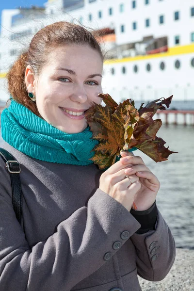 Kobieta Wysuszonym Liściem Klonu Stojąca Nabrzeżu Miasta Jesienią Ubrana Szary — Zdjęcie stockowe