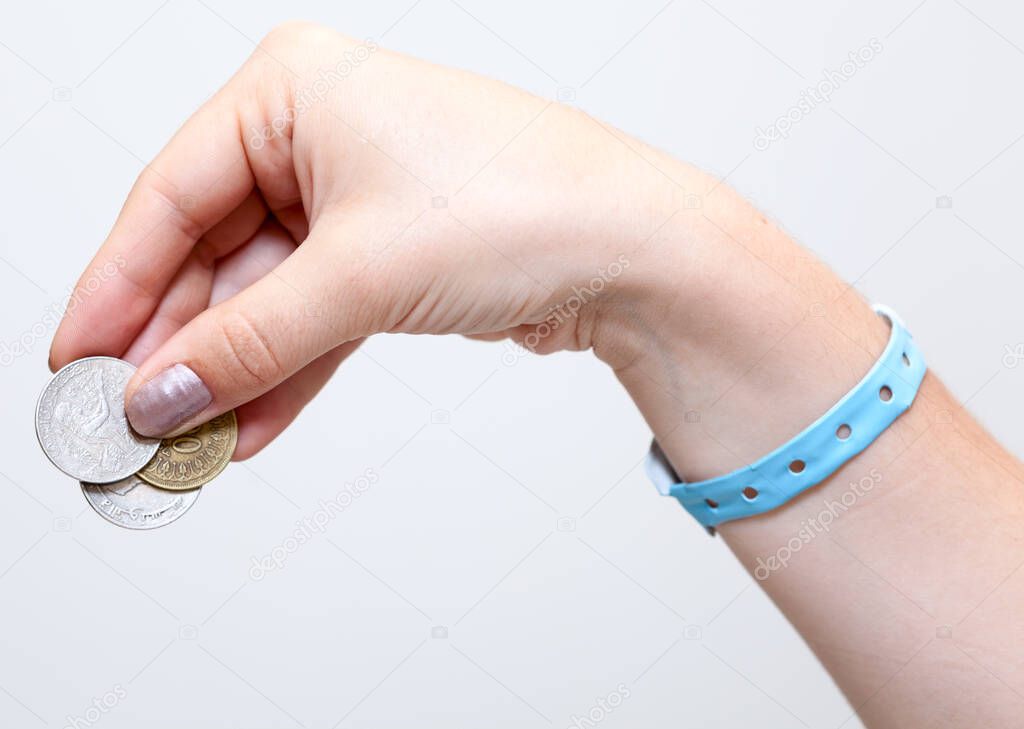 Female hand gives tip with coins money, grey background