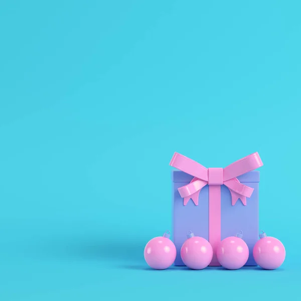 粉红色礼品盒与丝带弓和圣诞球在明亮的蓝色背景在柔和的颜色 极简主义概念 — 图库照片