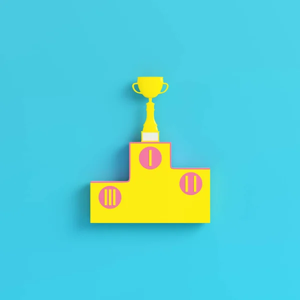 Pedestal amarelo com copo de troféu no fundo azul brilhante em pas — Fotografia de Stock
