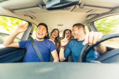 Arkadaşlar bir yol gezisi sırasında araba şarkı içinde. Çok kültürlü bir grup arkadaşıyla birlikte tatil için bırakarak. Ön ve arkadaki şarkı, gülen ve having fun iki kadın oturan iki adam