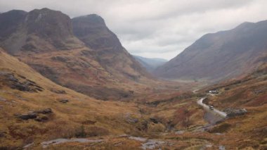 Doğal görünümü ile Dağlık İskoçya'da bir yol windiwng. Karamsar hava Glencoe yakınındaki İskoç dağlık. Sol belgili tanımlık are dağlardaki Glencoe üç kız kardeş bilir. Doğa ve seyahat kavramları