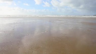 Bulutlar deniz rüzgarlı bir günde Wales, İngiltere'de Güney sahilde üzerinde. Islak kum su çevresinde rüzgar ile. Seyahat ve doğa kavramları