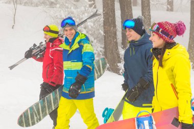 Arkadaş grubu kayak ve kar kurulu yamaçlarda eğleneceğiz karda yürüme. Bir grup genç insanlar giyen Kayak kıyafetleri ve gülümseyen kış spor sahne. Spor ve yaşam tarzı kavramları