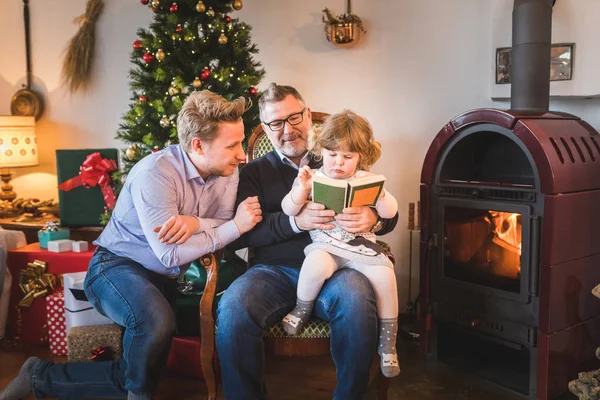 Küçük Kız Babası Dedesi Noel Gününde Bir Kitap Okuma Ile — Stok fotoğraf