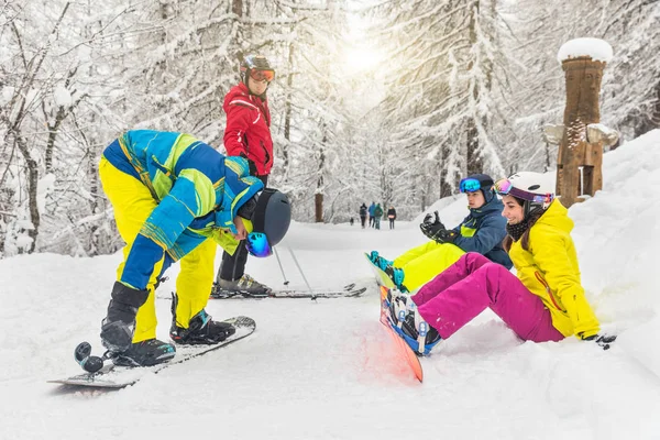 Group of friends with ski and snowboard on the snow going to have fun on the slopes. Winter sport scene with a group of young people wearing skiing clothes and getting ready. Sport and lifestyle concepts