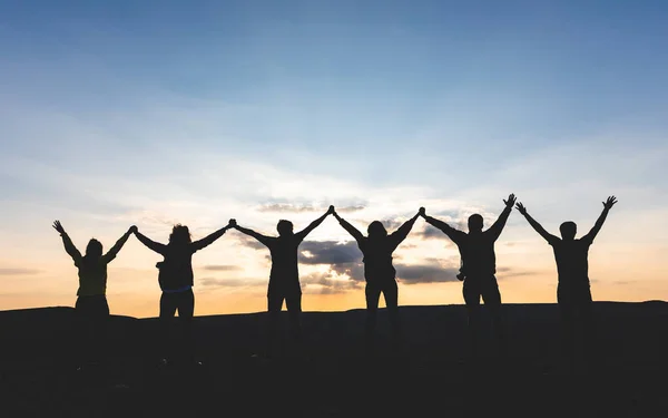 一群人举起双臂 手牵手 看着夕阳 成功人士和朋友在山顶上一起享受苏尼特 友谊在这张照片中展现 — 图库照片