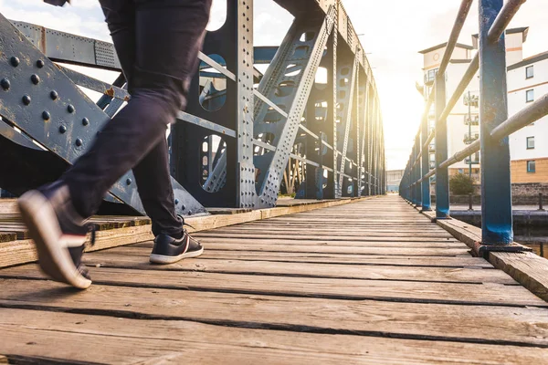 夕日橋を渡る男 木製の歩道橋を渡って歩く人の足に表示を閉じる — ストック写真