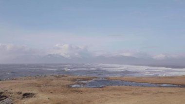 İzlanda, görünümü ile kar Hvalnes deniz feneri noktadan Dağları ve okyanus dalgaları. Güney İzlanda kıyısında güneşli ve rüzgarlı bir gün güzel ve epik görünümü. Sonsuz manzara ve ham doğa.