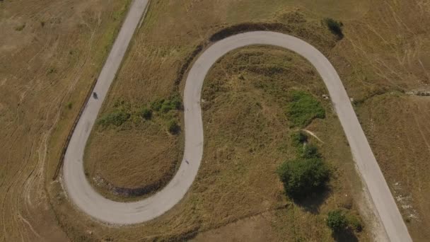 一个人在山路上驾驶摩托车的鸟图 摩托车在蜿蜒穿过乡村的道路上的无人机视频 运输和旅行概念 — 图库视频影像