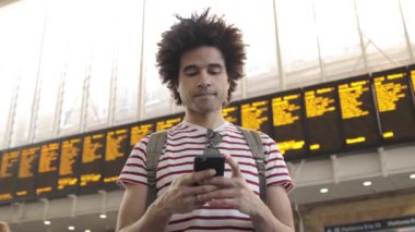 Tren istasyonundaki adam cep telefonuyla tarifeleri kontrol etti