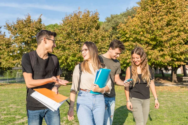 Estudiantes felices en el parque llevando libros y divirtiéndose —  Fotos de Stock