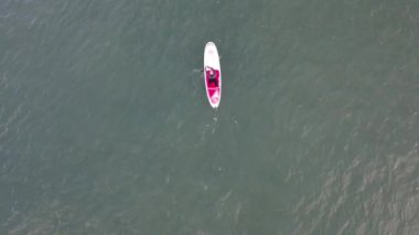 Adam spor yapıyor, kürek çekiyor, deniz kenarında, hava manzaralı.