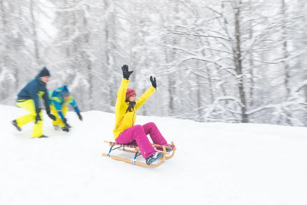 Vänner som har kul på snön glider med en liten släde — Stockfoto