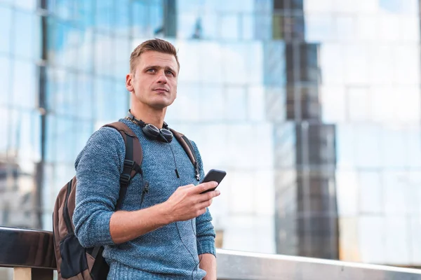 Pensive man using phone portrait with modern buildings on background - Thoughtful man alone in the city - Lifestyle and business concepts in capital city