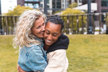 Birbirlerine sarılıp kucaklaşan mutlu çok ırklı sevgililer - lezbiyen çiftler, milenyum kadınları, Londra 'da mutlu bir hayat süren kızlar - LGBTQ konsepti karışık ırk güzel çiftler