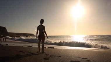 Silhouette view of a woman at seaside enjoying sea and sunset in Fuerteventura - Young woman on the beach looking at the ocean and relaxing