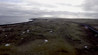 İzlanda Hava görünümünü kıyı şeridi ve dağ. Kahverengi ve gri taş bazı kar ve okyanus dalgaları, Dağları üzerinde arka plan ile. Kış İzlanda görünümünde. Seyahat ve macera kavramları