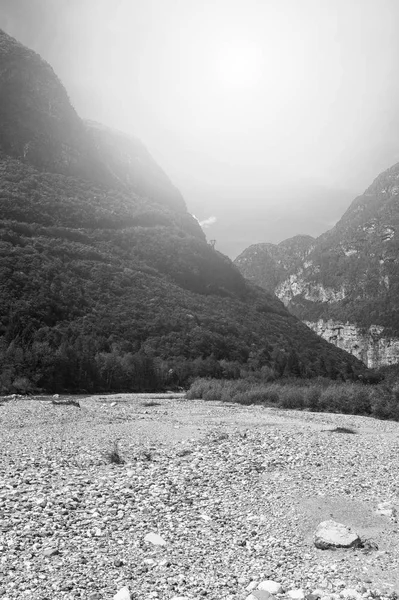 Morning mist in Italian Alps. View of the mountain dry riverbed in Italy at sunrise. Black and white picture