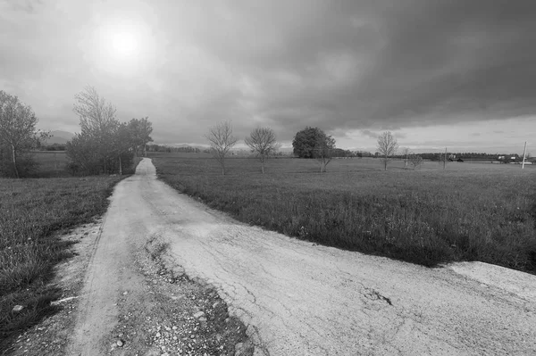 İtalyan Alpleri arka plan üzerinde kir yol Piedmont. Görünümü gündoğumu, eski kırık yolu ile dağ Vadisi. Siyah beyaz resim 