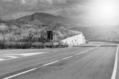 Gündoğumunda Sicilya tepelerinin manzarası. Asfalt yolu Sicilya adasının sık sık depremlerinden dolayı sütunlarla yükseldi. Siyah beyaz resim