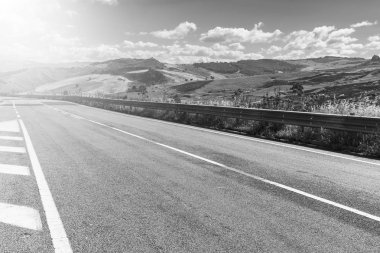 Gündoğumunda Sicilya tepelerinin manzarası. Asfalt yolu Sicilya adasının sık sık depremlerinden dolayı sütunlarla yükseldi. Siyah beyaz resim