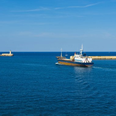 Kargo gemisi Valletta limanından ayrılıyor. Deniz fenerleri Malta limanlarına girişi gösteriyor.