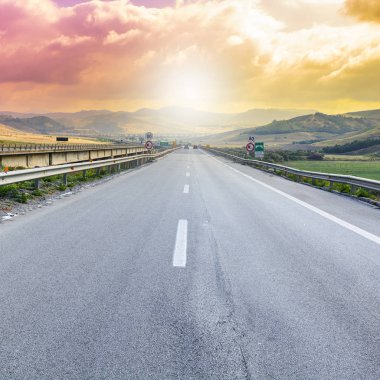 Gündoğumunda Sicilya tepelerinin manzarası. Asfalt yolu Sicilya adasındaki sık depremler nedeniyle sütunlarla yükseltildi.