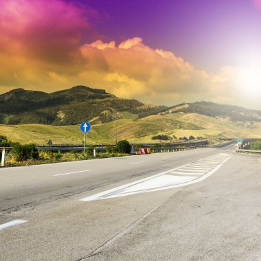Gündoğumunda Sicilya tepelerinin manzarası. Asfalt yolu Sicilya adasındaki sık depremler nedeniyle sütunlarla yükseltildi.
