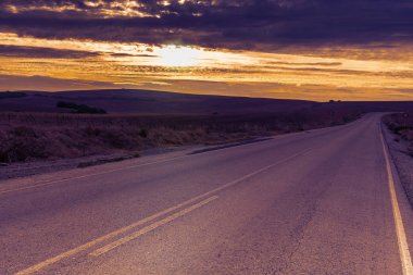 Tepeler arasındaki asfalt yol alanları İspanya güneş doğarken kaplı. Yasaklayıcı trafik işaret yok bir yolda sollama.