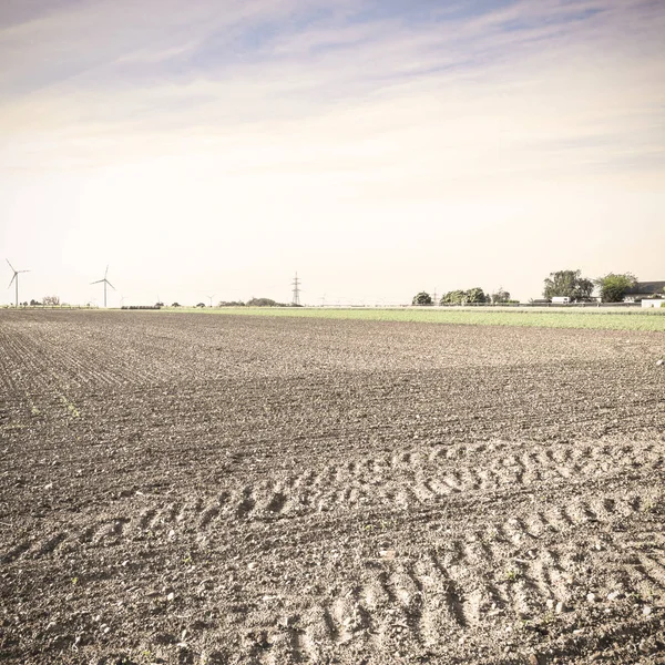 Plowed fields in Austrian landscape with modern wind turbines producing energy at sunrise