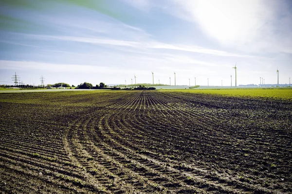 Plowed fields in Austrian landscape with modern wind turbines producing energy. Vintage style